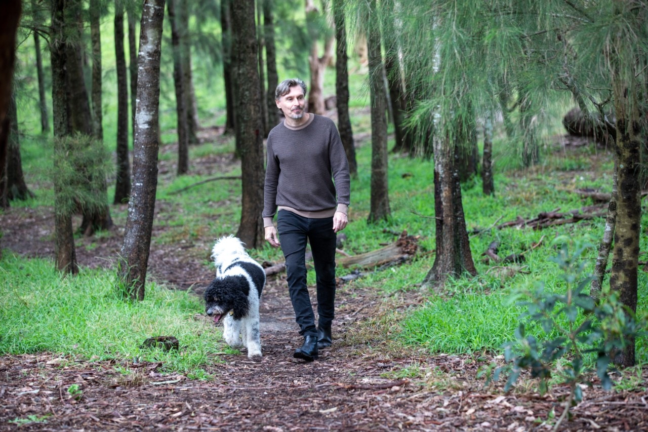 Michael Harvey walking through Sydney Park with his black and white dog