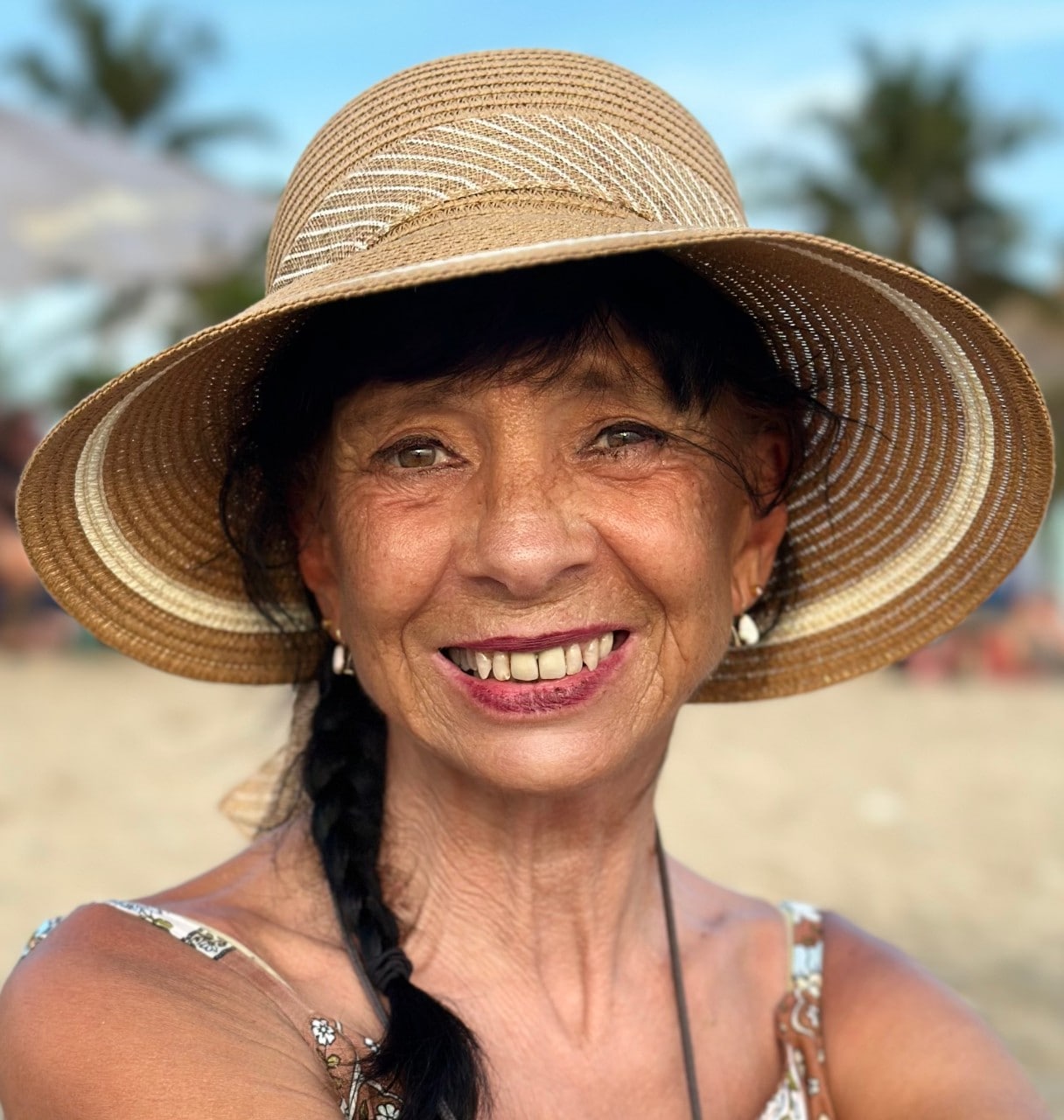 photo of indigenous woman smiling, wearing a sun hat