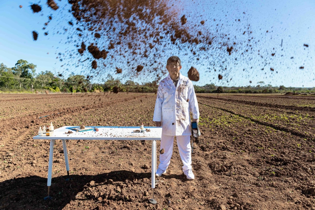 Professor Budiman Minasny in a field with soil in the air 