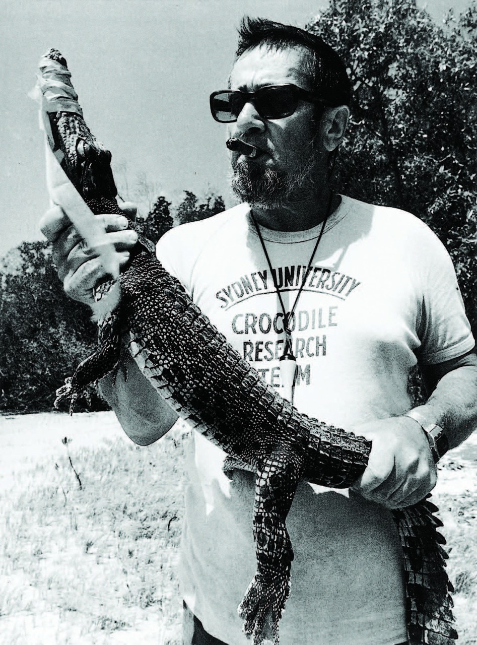 Harry Messel, from waist up, smoking a cigar and holding an alligator