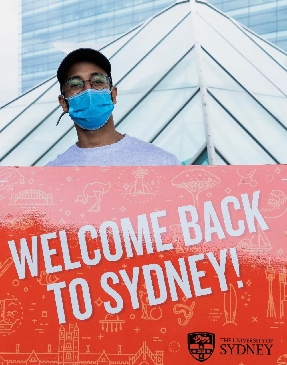 A boy holding the 'Welcome to Sydney' signboard 