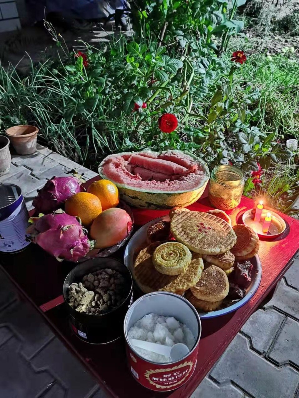 Table of food, fruits, mooncakes, candles, outside in a yard