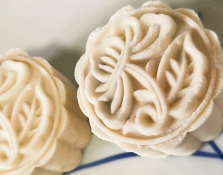 An image of snow skin mooncake, white in colour, with carving decorations on top
