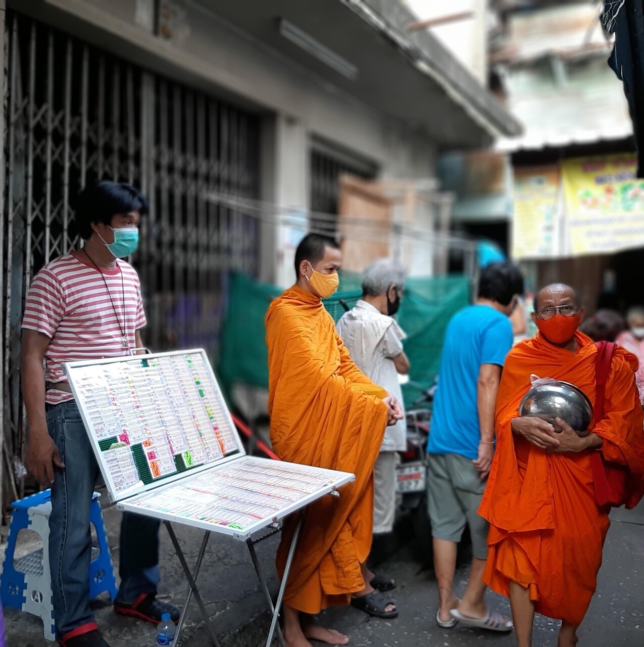 Photograph of monks and pedestrians wearing masks in Thailand