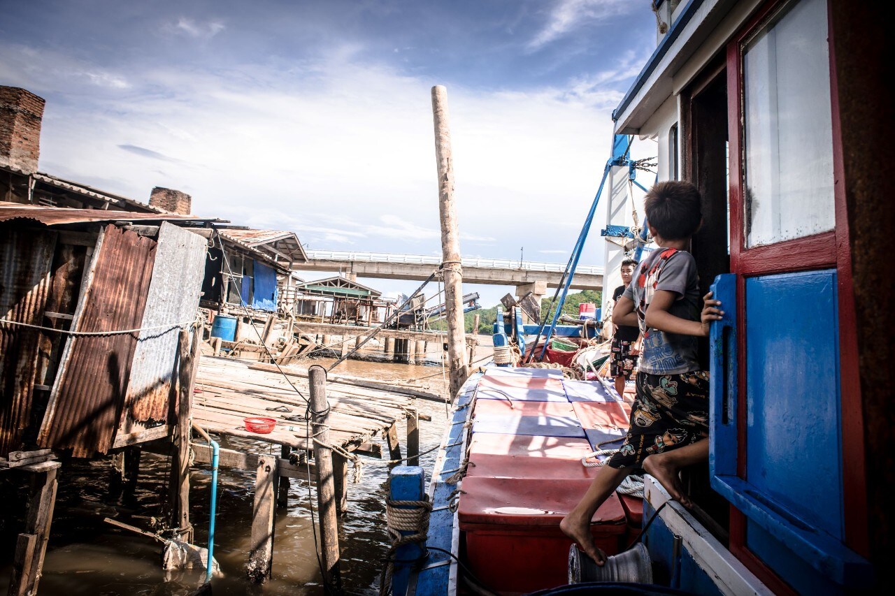Photograph of kids hopping on a boat in a fishing community in Thailand